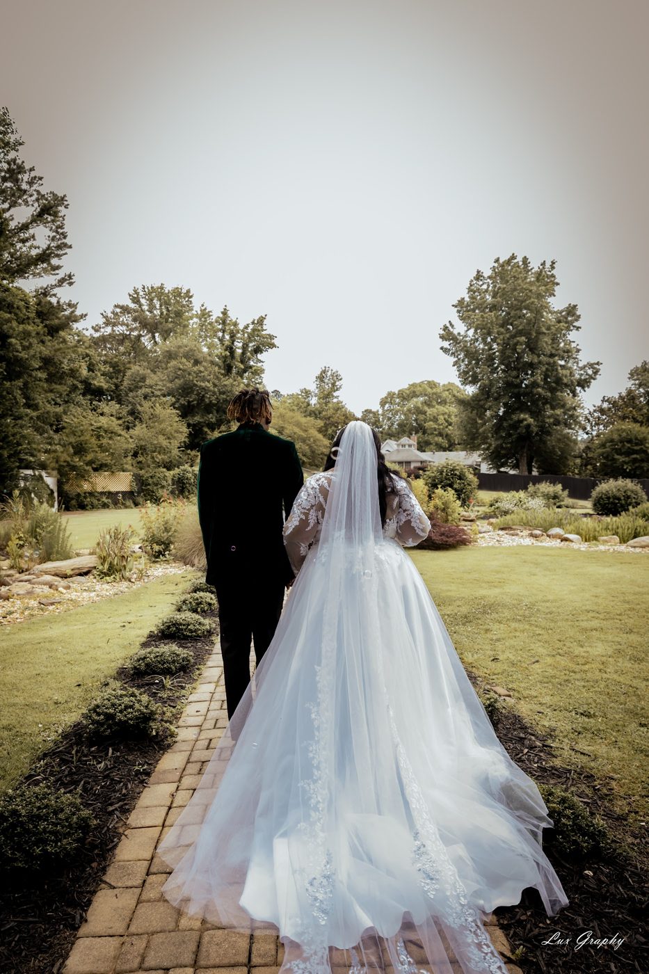 Bride walking a garden path, photographed by Lux Graphy